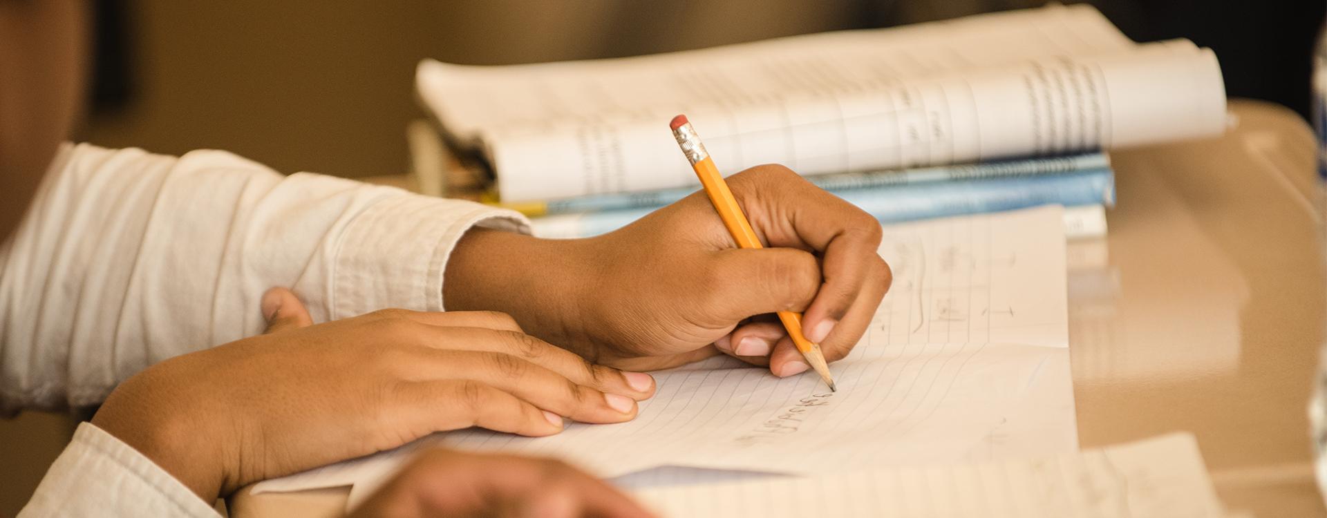 Student writing at a desk